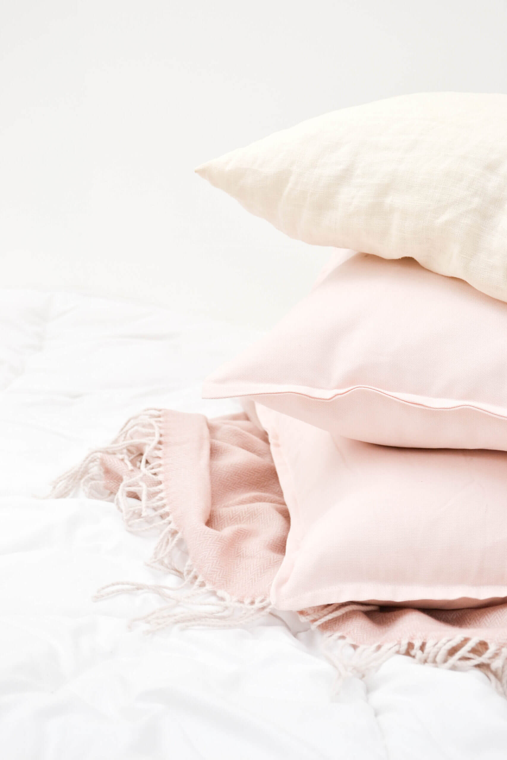 soft pink pillows on a white duvet bed covering